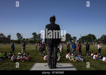 Hiromitsu Honda, Mitte, Planung Abteilung Direktor des Chigoku-Shikoku Verteidigung Bureau, spricht zu den Athleten vor den USA und Japan Jugend-Fußball-Turnier am Suo-Oshima, Japan, Okt. 21, 2018. Jugend Sport Marine Corps Community Services Iwakuni-Programms organisiert die Veranstaltung als Teil seiner Mission Kinder im Alter von drei bis 15 Chancen in einer Vielzahl von Sport teil zu haben. Stockfoto