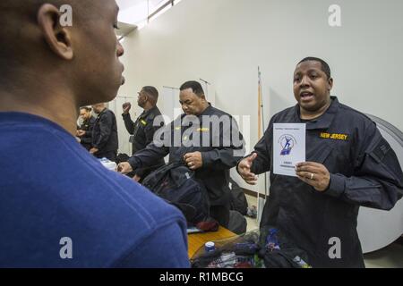 Ein Mitglied der New Jersey Youth ChalleNGe Akademie Kader erklärt die Bedeutung der Kadett Handbuch zu einer Klasse 49 Kandidaten während der Verarbeitung, an dem gemeinsamen militärischen und Family Assistance Center der National Guard Armory in Bordentown, N.J., 23. Okt., 2018. In den nächsten zwei Wochen der 22-wöchige Programm, die Kandidaten eine akklimatisierung Phase wo Sie körperliche, geistige und soziale Disziplin des Programms einstellen werden. Die freiwillige pädagogische Programm bietet 16- bis 18-jährige Schulabbrecher eine strukturierte Wohn- Programm in einer quasi-militärischen Umfeld, in dem Sie Stockfoto