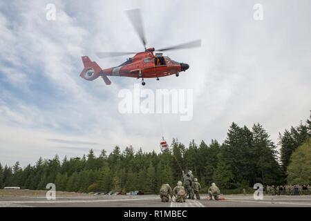 BANGOR, Washington (Okt. 23, 2018) Segler aus lokalen ballistischer Flugkörper und Raketen-U-Boote Praxis mit einem rescue Hoist von US Coast Guard MH-65 Dolphin Helikopter geführte, Coast Guard Air Station Port Angeles zugewiesen, während der medizinischen Evakuierung (Medevac) Bohrer Ausbildung bei Naval Base Kitsap-Bangor. Stockfoto