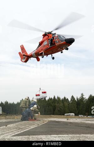 BANGOR, Washington (Okt. 23, 2018) Segler aus lokalen ballistischer Flugkörper und Raketen-U-Boote Praxis mit einem rescue Hoist von US Coast Guard MH-65 Dolphin Helikopter geführte, Coast Guard Air Station Port Angeles zugewiesen, während der medizinischen Evakuierung (Medevac) Bohrer Ausbildung bei Naval Base Kitsap-Bangor. Stockfoto