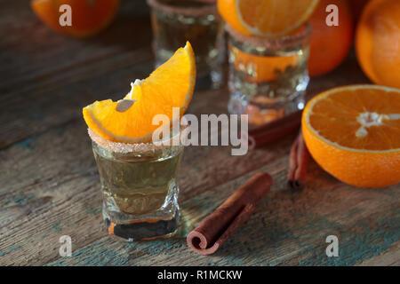 Kleine Gläser tequila, Orangenscheiben und Zimtstangen. Stockfoto
