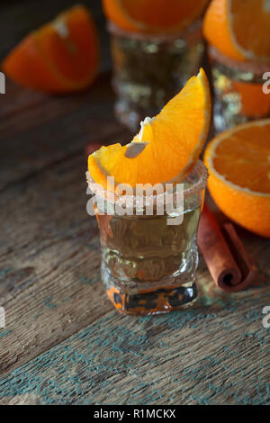 Kleine Gläser tequila, Orangenscheiben und Zimtstangen. Stockfoto