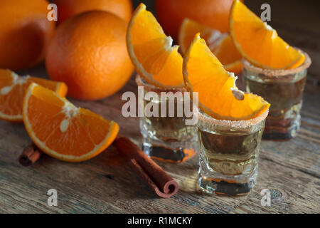Kleine Gläser tequila, Orangenscheiben und Zimtstangen. Stockfoto
