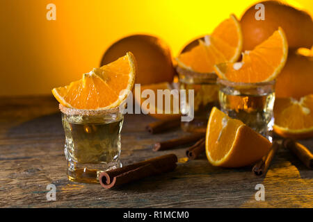 Kleine Gläser tequila, Orangenscheiben und Zimtstangen. Stockfoto