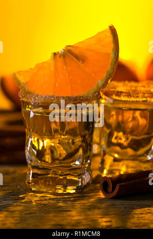 Kleine Gläser tequila, Orangenscheiben und Zimtstangen. Stockfoto