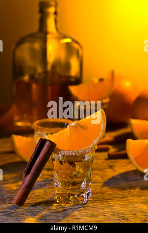 Kleine Gläser tequila, Orangenscheiben und Zimtstangen. Stockfoto