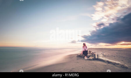 Frau sitzt am Meer auf einer paradiesischen Strand Insel, durch das Paradies umgeben, schöne Sonnenuntergang oder Sunrise Stockfoto