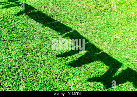 Silhouetten und Formen der Wäsche trocknen auf die Zeichenfolge im Hinterhof, Sonne Licht und Schatten auf grünem Gras. Stockfoto