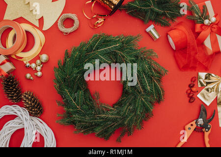 Flach mit Pine Tree Branches im Kreis und Dekorationen für Weihnachten Kranz auf Rot isoliert angeordnet Stockfoto