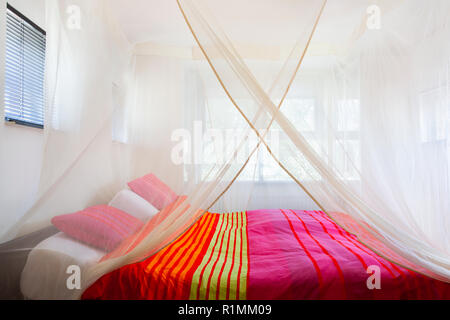 Bett mit bunten Decke unter einem Moskitonetz Stockfoto