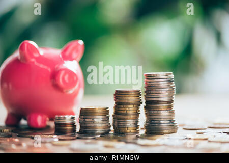 Gestapelte Münzen und rosa Sparschwein, Nahaufnahme Stockfoto