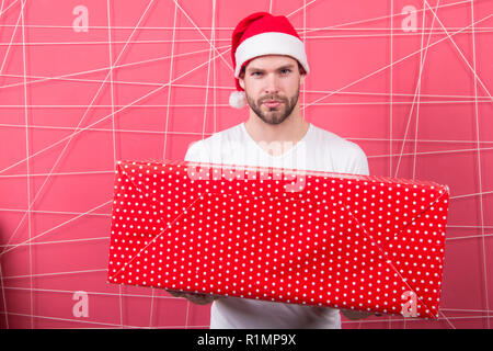 Am Morgen vor Weihnachten. lieferung Weihnachtsgeschenke. Mann den Urlaub genießen. Mann in santa hut halten Weihnachtsgeschenk. Frohe Weihnachten und schöne Feiertage. Helle Erinnerungen. Stockfoto