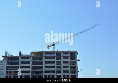 Gebäude bei Bauarbeiten in der Stadt, mit einem Kran gegen den blauen Himmel Stockfoto