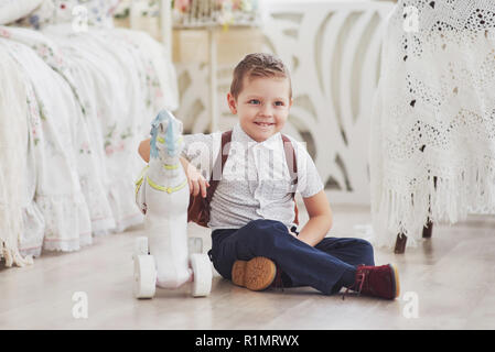 Kleiner Junge mit einem Rucksack sitzt im Kinderzimmer und spielt Spielzeug. Zum ersten Mal in der Schule. Glückliche Kindheit Stockfoto