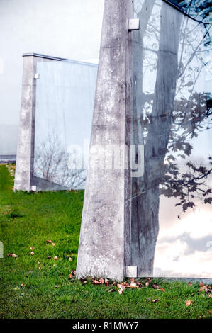 Moderne öffentliche architektonische Attraktion von Zement und Windows mit reflektiertem Baum Silhouette und Wolken im Herbst Landschaft - Kontraste der coolen Urban Design Gebäude und Herbst Natur im Sonnenuntergang Stockfoto