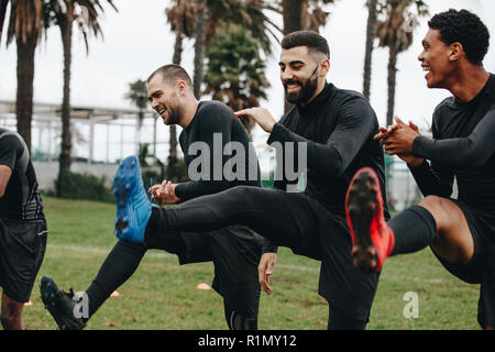 Fröhliche Fußball-Spieler tun, Warm-up Übungen auf dem Feld vor dem Spiel. Gerne Fußballer tun Beinheben stehend auf dem Feld. Stockfoto