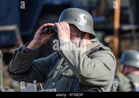 Reenactor, Nachstellung eines deutschen Soldaten aus dem Zweiten Weltkrieg, der durch ein Fernglas schaut. Infanteristen der Wehrmacht. Einheitlich Stockfoto