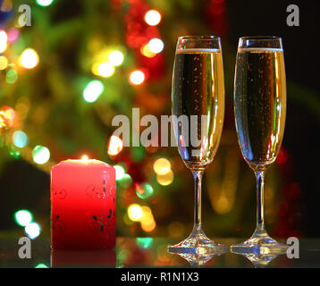 Gläser mit Champagner und Kerzenlicht gegen festliche Lichter Stockfoto