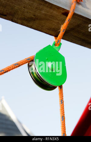 Eine feste Riemenscheibe mit einem orange Seil vor einem blauen Hintergrund isoliert Stockfoto