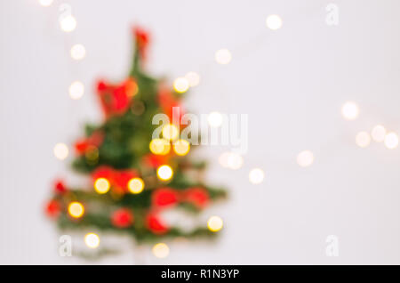 Unscharfer Hintergrund. Weihnachtsbaum auf einem weißen Hintergrund. Girlande, die an der Wand. Weihnachtsbaum in einem weißen Raum für Weihnachten. Stockfoto