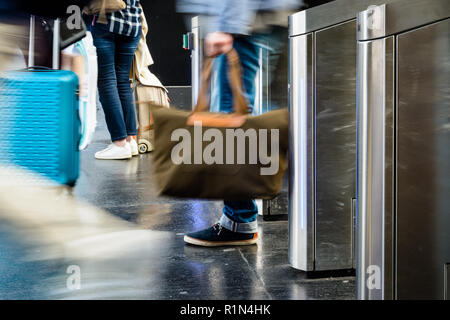 Menschen mit Taschen und Koffer Rollen durch Edelstahl ticket Tore in einem öffentlichen Verkehrsmittel Bahnhof in Paris mit Bewegungsunschärfe. Stockfoto