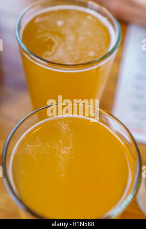 In der Nähe von zwei hohe Gläser Bier auf einen Tisch in einem Restaurant Stockfoto