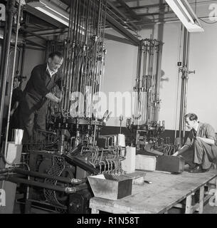 1950er Jahre, Arbeitnehmer in Overalls an der stets bereit ist, Fabrik, Wald Rd, London die Kontrolle der Herstellung von Anlagen für die Produktion von Zink-Kohle-Batterien verwendet. Stockfoto