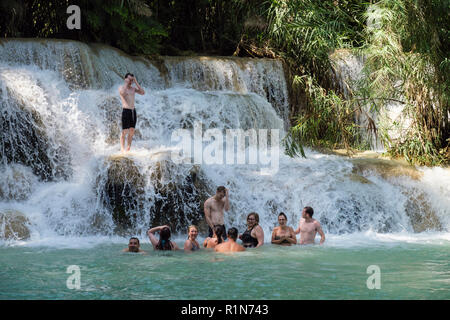 Junge Menschen, die Spaß wild Schwimmen im kühlen Wasser des Pools am Tat Kuang Si Wasserfällen mit Wasser Kaskadierung über Felsen. Luang Prabang, Laos, Asien Stockfoto