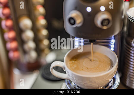 Espresso Kapseln und Maschine Maker auf einem Holztisch, blur Kaffeepads und Bohnen Hintergrund Stockfoto