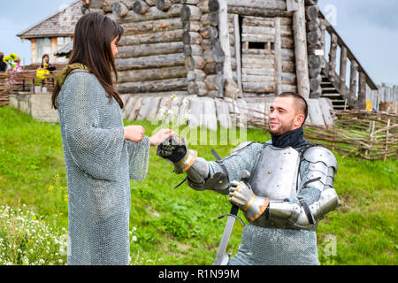 Ein Ritter in Rüstung gibt Kamille zu seiner Dame Herz. Ritterlichen Rüstung und Waffe. Semi-antik Foto. Stockfoto