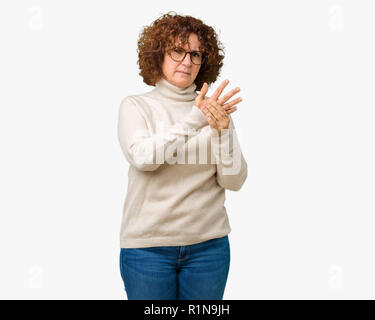 Schöne Mitte ager ältere Frau mit Rollkragen Pullover und Gläser über isolierte Hintergrund Schmerzen an den Händen und Fingern, Arthritis Einfl Stockfoto