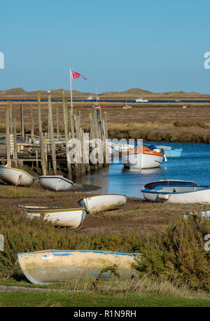 Morston Kai und Creek in atmosphärischen North Norfolk. Kleine Boote auf alte hölzerne Stege und Pontons auf einem hellen herbstlichen Tag günstig Stockfoto