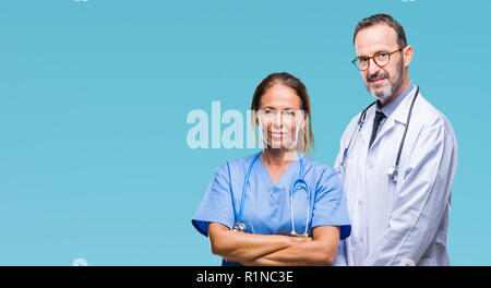 Mittleres Alter spanischer Ärzte Partner Paar mit medizinischen gleichmäßig über isolierte Hintergrund mit ernsten Gesichtsausdruck. Einfache und natürliche looki Stockfoto