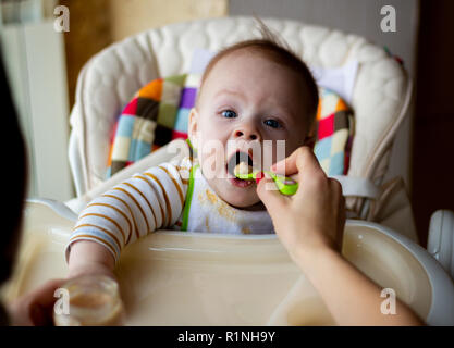 Die erste Fütterung der Baby aus dem Löffel. Mom-feeds Baby homogenisiert gehackt Essen mit dem Löffel. Kinderbetreuung. Lifestyle. Stockfoto