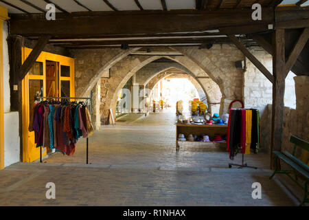 Agen, Frankreich - April 6th, 2017: Unter den Arkaden des Place des Arcades'Central Square in Monflanquin, Lot-et-Garonne, Frankreich. Diese malerische Stadt ist Mitglied der Schönsten Dörfer von Frankreich (Les Plus beaux villages de France) Association und ist gedacht, um eine historisch gesehen die intakten Beispiele für eine Mittelalterliche Bastide. Stockfoto