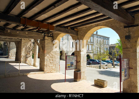 Agen, Frankreich - April 6th, 2017: Unter den Arkaden des Place des Arcades'Central Square in Monflanquin, Lot-et-Garonne, Frankreich. Diese malerische Stadt ist Mitglied der Schönsten Dörfer von Frankreich (Les Plus beaux villages de France) Association und ist gedacht, um eine historisch gesehen die intakten Beispiele für eine Mittelalterliche Bastide. Stockfoto