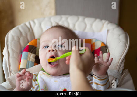 Die erste Fütterung der Baby aus dem Löffel. Mom-feeds Baby homogenisiert gehackt Essen mit dem Löffel. Kinderbetreuung. Lifestyle. Stockfoto