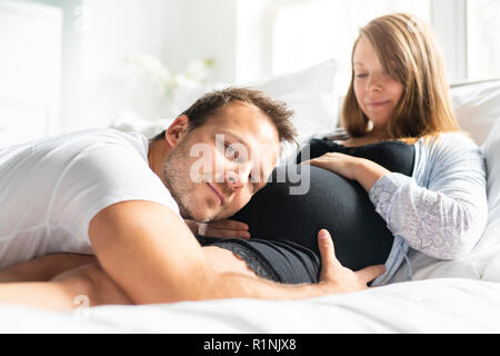 Ein Eltern im Bett erwartet ein kleines Baby, romantische Momente für schwangere Paar Stockfoto