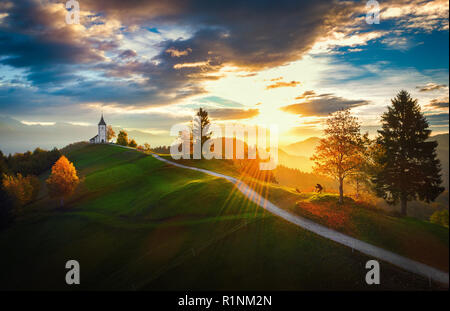 Jamnik, Slowenien - Luftbild über die Kirche St. Primoz in Slowenien in der Nähe von jamnik mit schönen Wolken und die Julischen Alpen im Hintergrund. Stockfoto