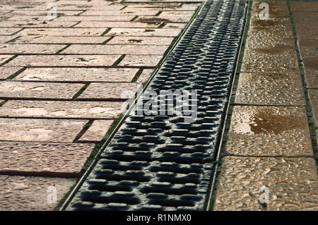 Entwässerung gepflastert mit roten und gelben Fliesen, Entwässerung auf dem Bürgersteig, der Kühlergrill ist eine Regenrinne auf dem Bürgersteig Stockfoto