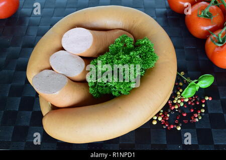 Lyoner ist eine Wurst Feinkost auf einem schwarzen Tischset. Lyoner ist ein wurst-delikatessen in einem schwarzen Tischset. Stockfoto