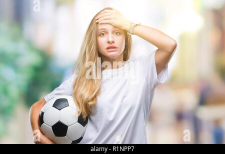 Junge hübsche blonde Frau mit Fußball über isolierte Hintergrund mit Hand betonte am Kopf, mit Scham und Überraschung Gesicht schockiert, wütend und Stockfoto