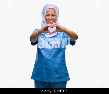 Mittleres Alter älteren arabischen Krankenschwester Frau, tragen, Hijab über isolierte Hintergrund lächelnd in Liebe mit Herz und Formen mit den Händen. Romantische Konzept. Stockfoto