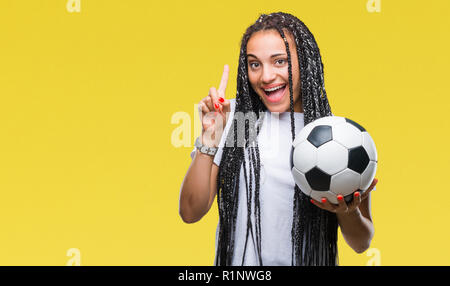 Junge geflochtenes Haar African American Girl holding Fußball über isolierte Hintergrund überrascht mit einer Idee oder Frage Zeigefinger mit glücklichen Fa Stockfoto