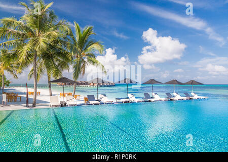 Liegestühle und Infinity Pool über fantastische tropische Lagune. Luxus und Urlaub Konzept Stockfoto