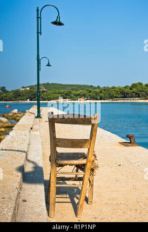 Alter Holzstuhl auf einem Pier vor Koukounaries Strand, morgen auf der Insel Skiathos, Griechenland Stockfoto