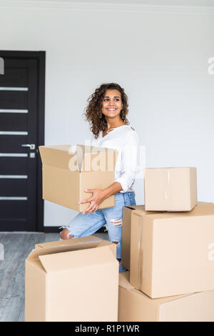 Glückliche Frau bei Kartons Kisten verschieben. Junges Mädchen Vermittlung von Innenraum und Auspacken im neuen Appartementhaus nach Hause. Stockfoto