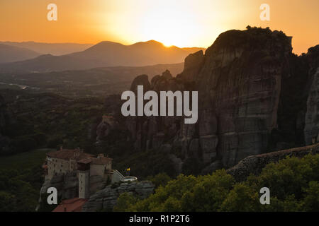 Die riesigen Felsen mit den Klöstern und Sonnenuntergang hinter die Berge in der Ferne in Meteora, Thessalien, Griechenland Stockfoto