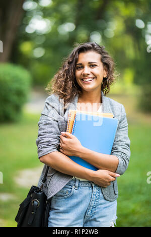 Ziemlich heiter Student an der Kamera, Notebook lächelnd auf dem Campus an der Hochschule Stockfoto