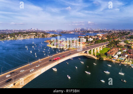 Kfz-Verkehr auf mehrspurigen Gladesville im Hinblick auf die Stadt Sydney CBD auf Horizont von Parramatta River mit Boote und Yachten. Stockfoto